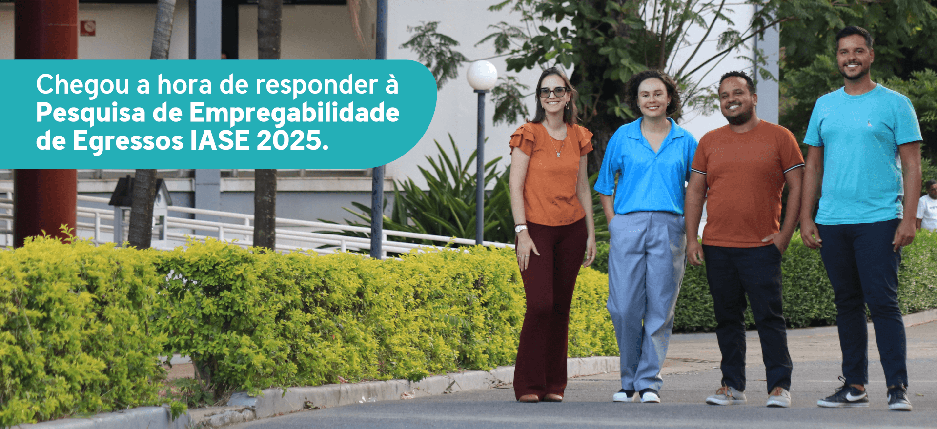 Foto com dois homens e duas mulheres no campus da PUC Minas, com a frase 'Chegou a hora de responder à Pesquisa de Empregabilidade de Egressos IASE 2025'